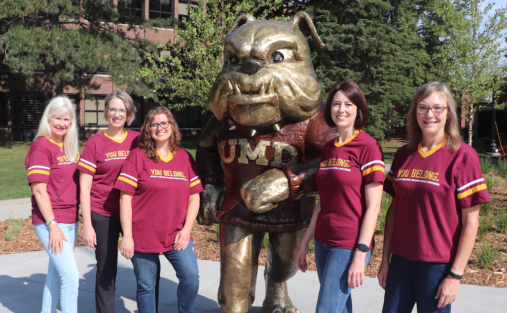Five advisors stand with bronze bulldog sculpture