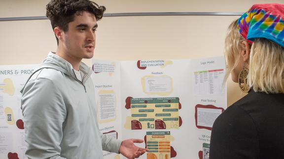 Chris Mahady talking to another student with a poster presentation in the background