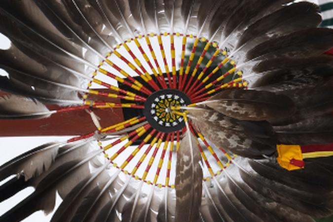 Close up of an American Indian feathery headdress with yellow and red beaded patter in the middle