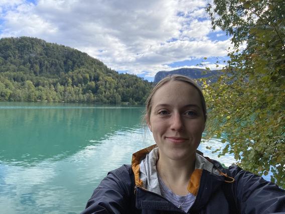 Molly Hughes hiking in Slovenia with a lake and mountains in the background
