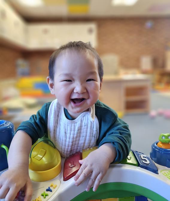 infant joyously smiling by a large toy