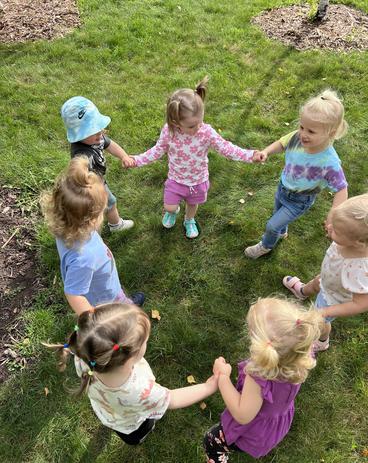 Toddlers in a circle holding hands outside