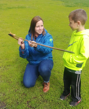 Elizabeth Reetz showing a young child a wooden spear