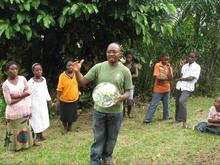 Edwin Nganji holding a globe in front of several young students
