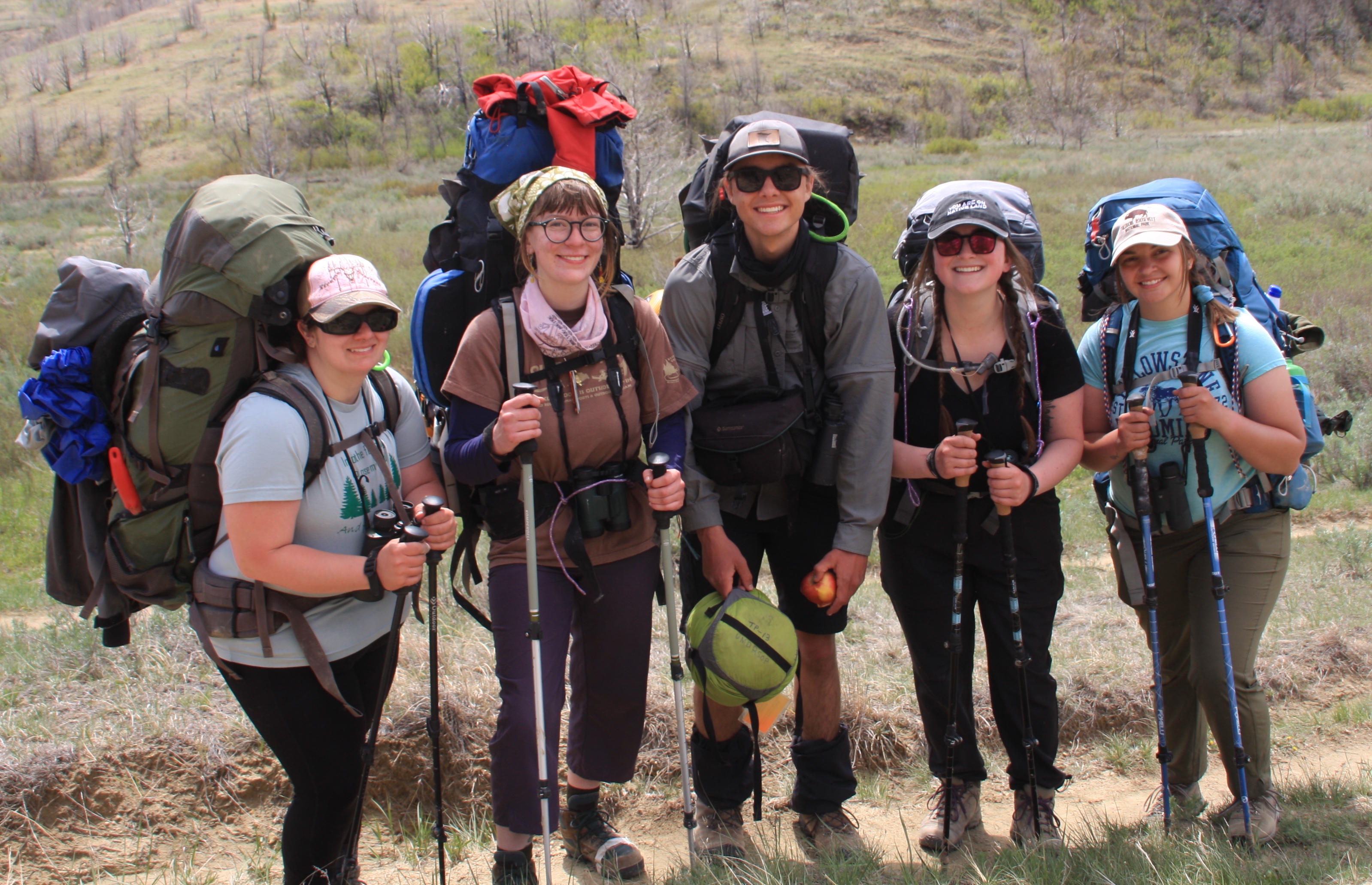 A group of students wearing hiking gear smiling for a photo while navigating through the Badlands of North Dakota