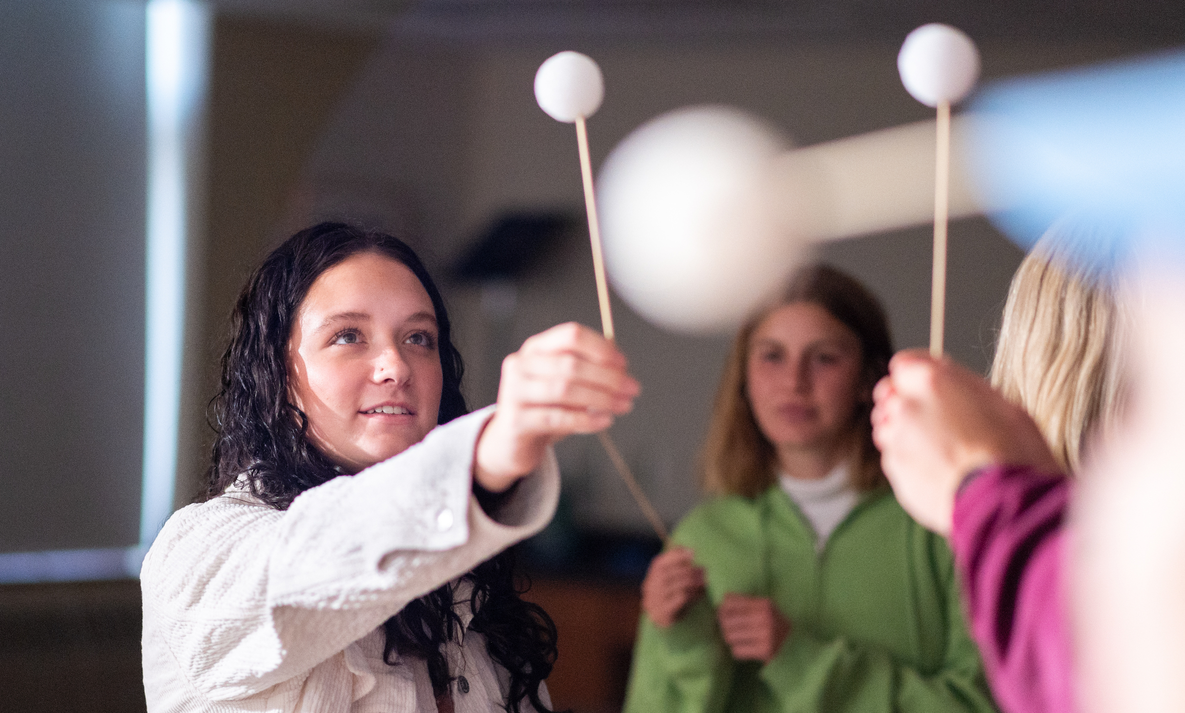 Teaching Science and Environmental Education class doing an exercise with a ball on a stick and lighting to simulate the moon and sun