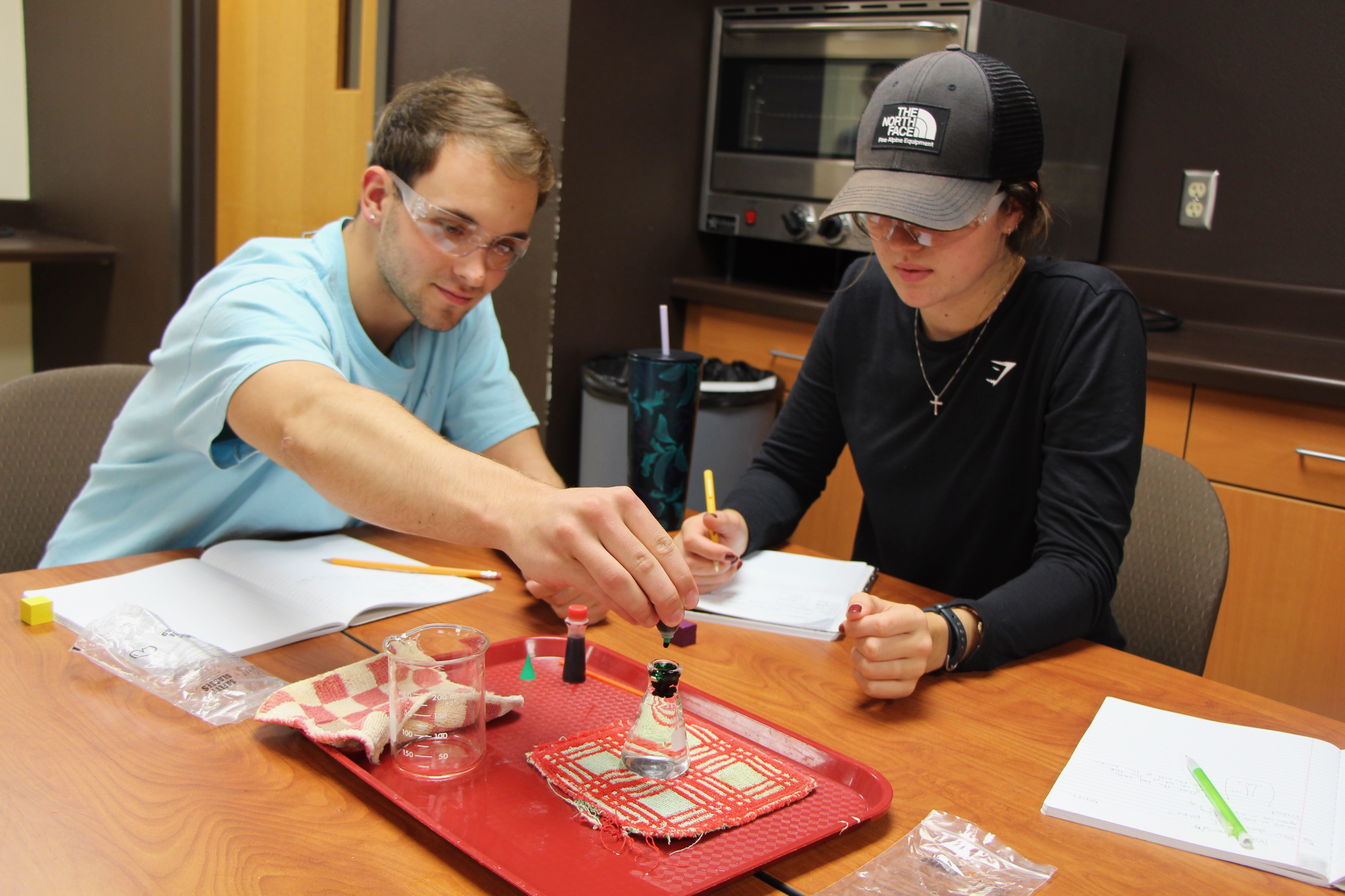 Two students experimenting with beakers and colorful liquids