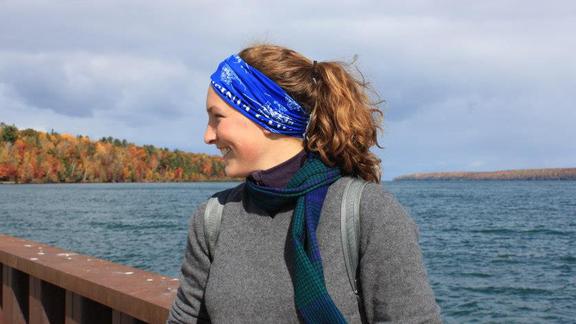 Hillary Olsen looking off to the side and smiling with Lake Superior and fall foliage in the background