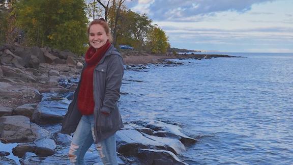 Erin Cecil standing at the edge of a lake on a rocky shore