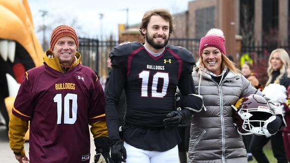 Johnny McCormick wearing his football uniform, smiling and walking with his parents