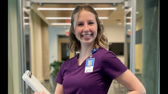 Annika Juenemann, from UMD's department of Communication Sciences and Disorders smiling for a photo in purple nursing scrubs