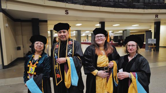 Image of Thelma, Brian, Priscilla and Marti with their robes and caps on at commencement