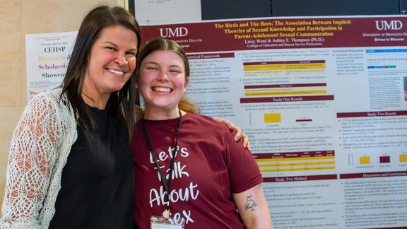 Ashley Thompson and Lizzy Benson in front of a research poster