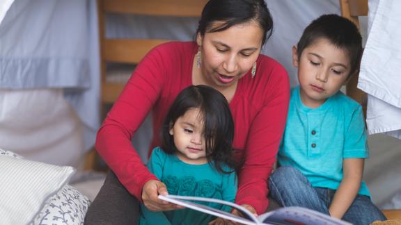 American Indian mother and children reading a book together
