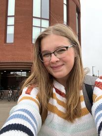 picture of Ella in a striped sweater in front of the entrance to the Library