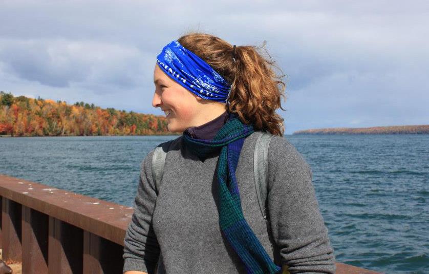 Hillary Olsen looking off to the side and smiling with Lake Superior and fall foliage in the background
