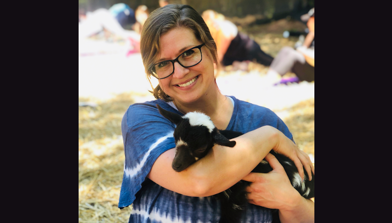 Stacy Seminara smiling, holding a small, black and white goat