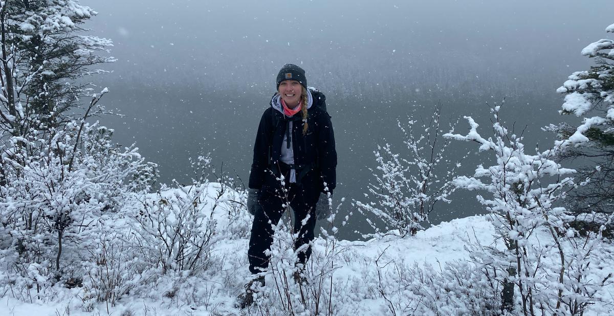 Sadie Shervheim, UMD public health graduate smiling for a photo in the snow in front of Lake Superior