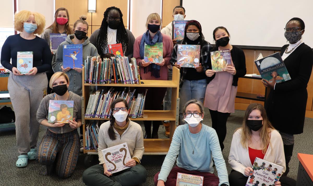 Group of students and faculty, masked and holding children's books