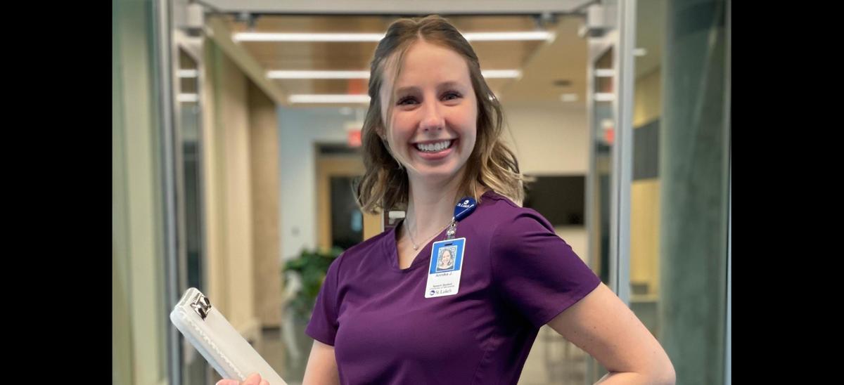 Annika Juenemann, from UMD's department of Communication Sciences and Disorders smiling for a photo in purple nursing scrubs