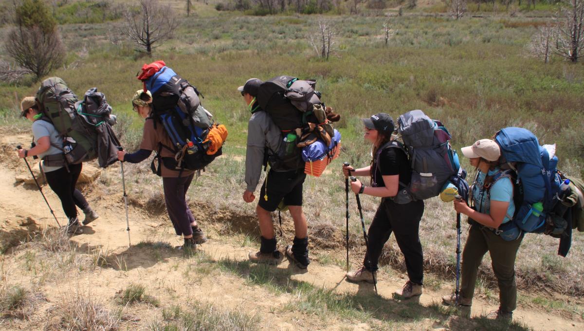 A group of students with hiking gear backpacking through the Badlands in South Dakota