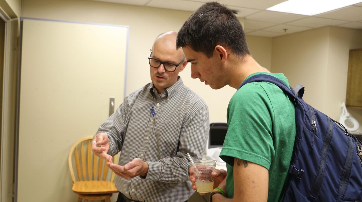 UMD faculty member showing a student an auditory hearing device
