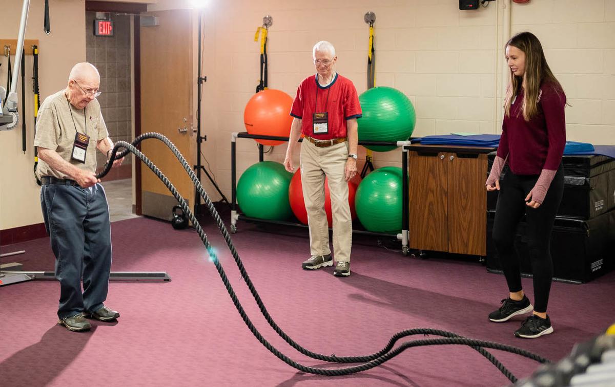 two older adults learning to use ropes with student looking on