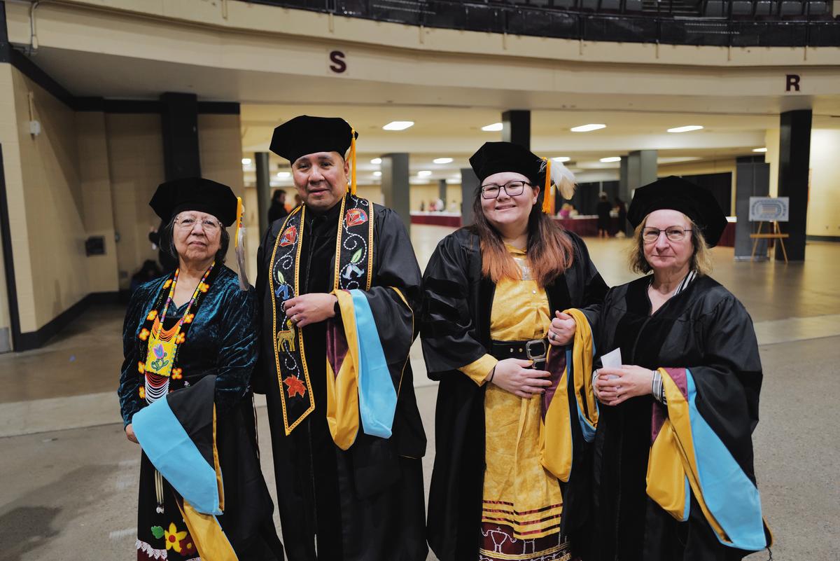 Image of Thelma, Brian, Priscilla and Marti with their robes and caps on at commencement