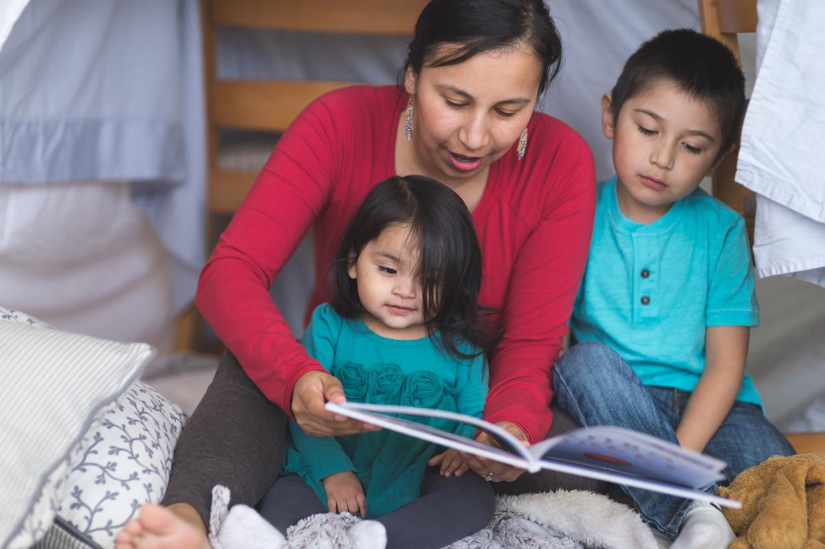 American Indian mother and children reading a book together