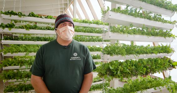 Karl Becker standing in front of a wall of microgreens in the deep winter greenhouse