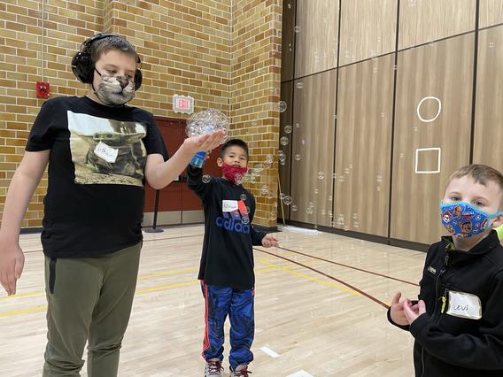 three enthusiastic kids wearing masks in the gym