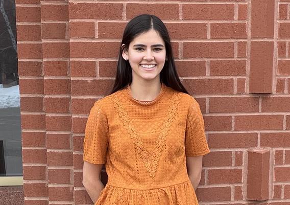 Mary Parasatoon, a umd student smiling for a photo behind a brick wall