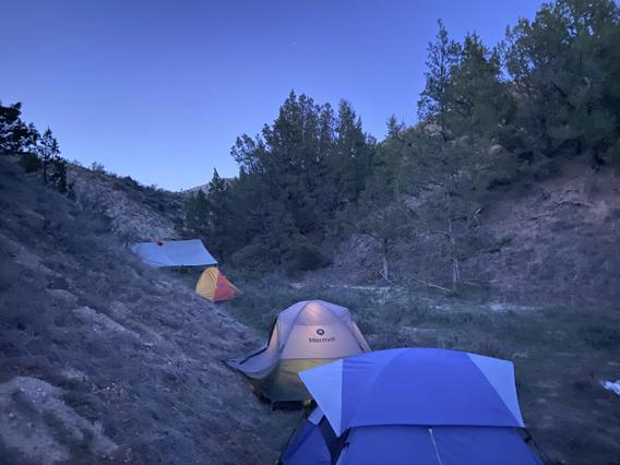3 tents nestled between two hills in the Badlands of North Dakota for a school-assigned backpacking trip