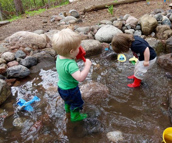 Children playing with water toys in a stream
