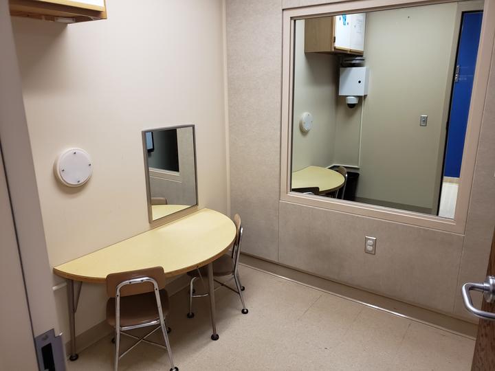 clinic therapy room includes small half moon shaped table with two chairs along left wall and mirror along right wall