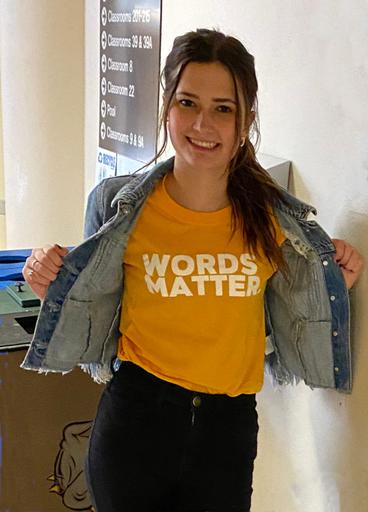 Courtney Webster wearing a yellow t-shirt that says "Words Matter"