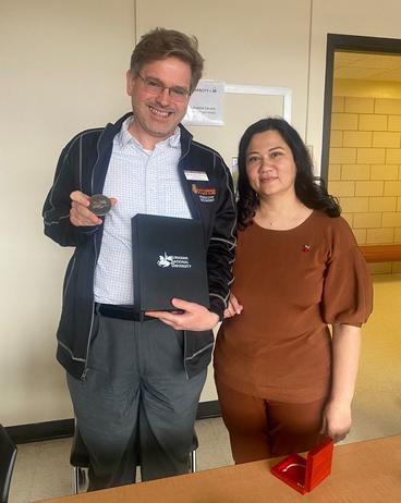 Associate Dean Scott Carlson holding a gift from the Kazakh scholars and standing next to  Aliya Mambetalina 