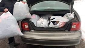 open car trunk filled with plastic bags of clothing