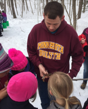 AISES student Aaron Moller showing students how a maple tap was made